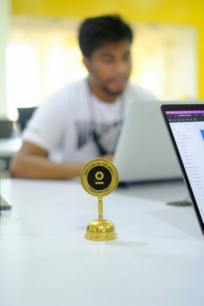 Blurred background office setup featuring an Employee of the Month trophy with a focus on modern work culture.